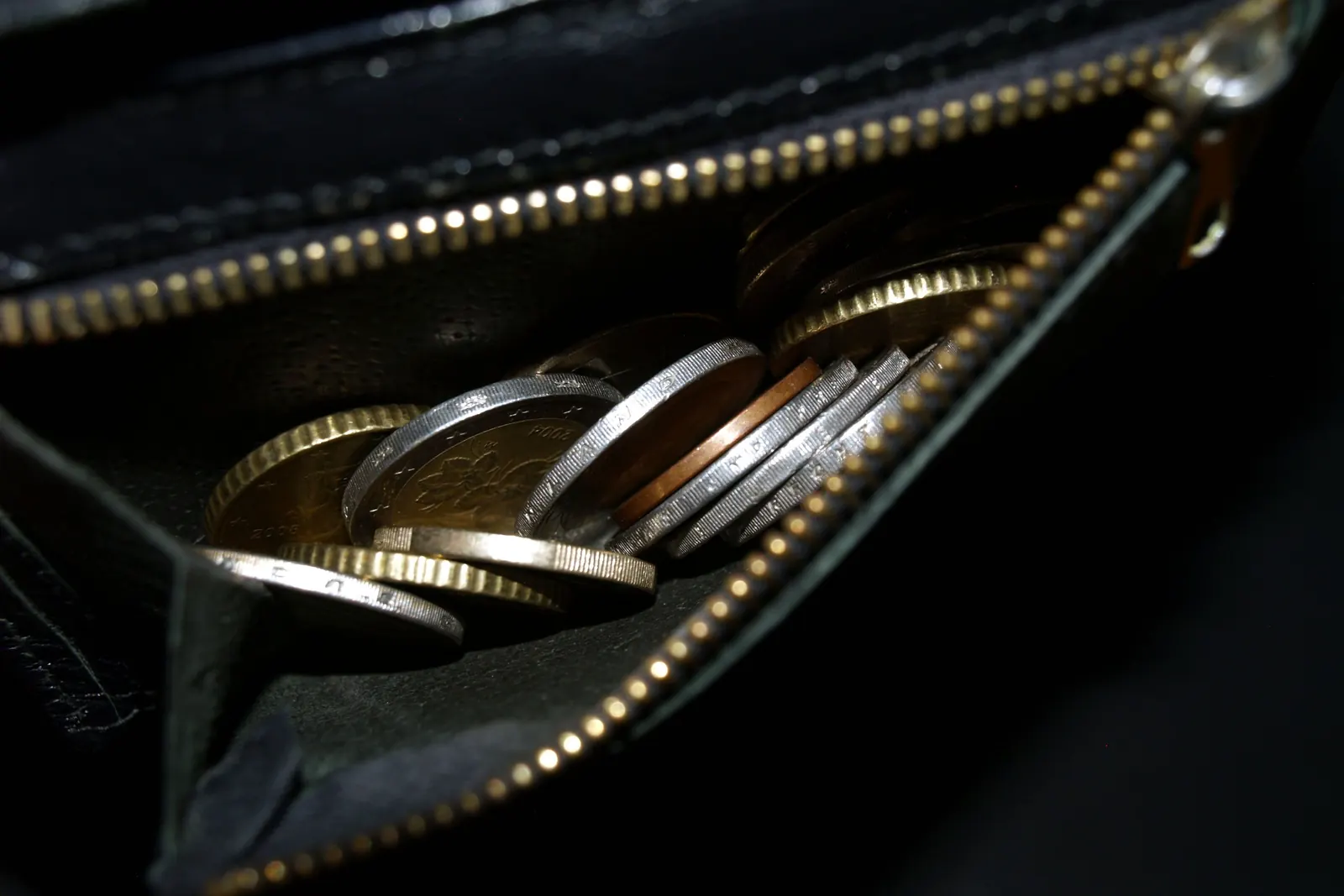Pièces en euros dans un porte-monnaie, vues par la tranche.
