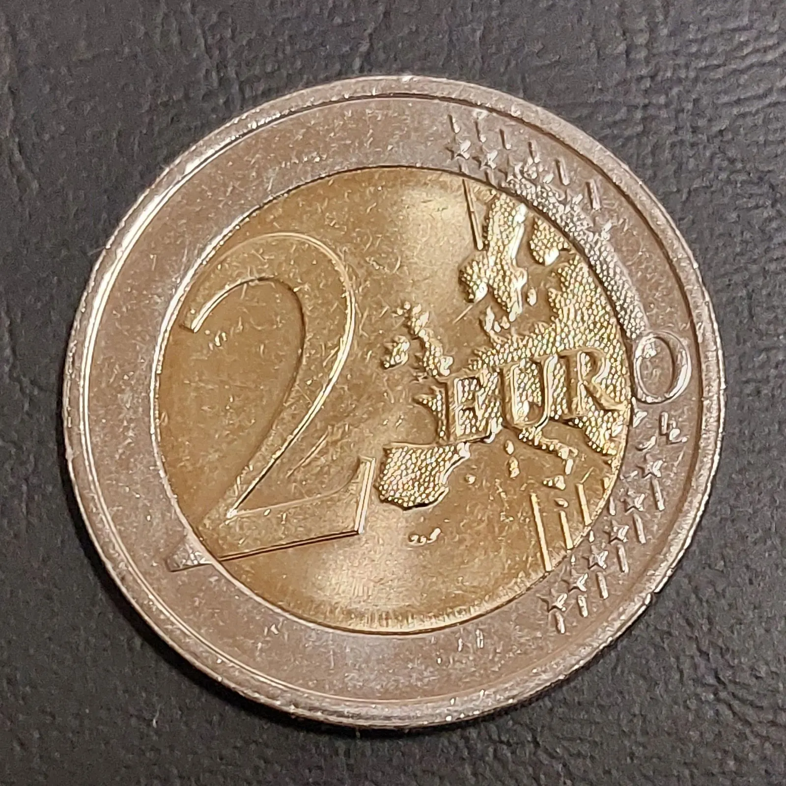 Photo de la face commune d'une pièce de 2 € : carte de l'Europe du modèle 2007, douze étoiles sur l'anneau, mention 2 EURO